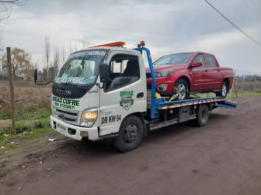 Grúa plataforma trasladando camioneta roja en Curicó