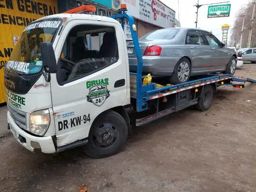 Grúa Cofré remolcando auto sedán gris en Curicó