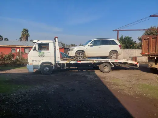 Grúa plataforma trasladando SUV blanco