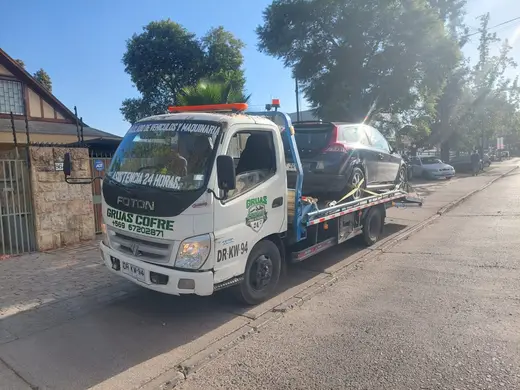 Grúa Cofré con auto en plataforma al amanecer